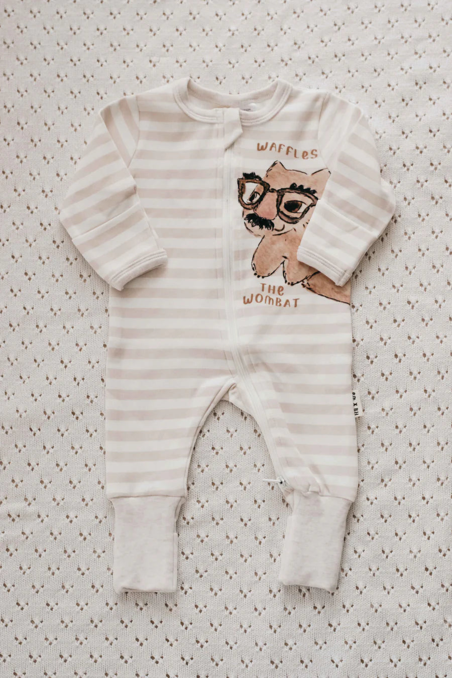Striped baby romper with cartoon character on a patterned surface