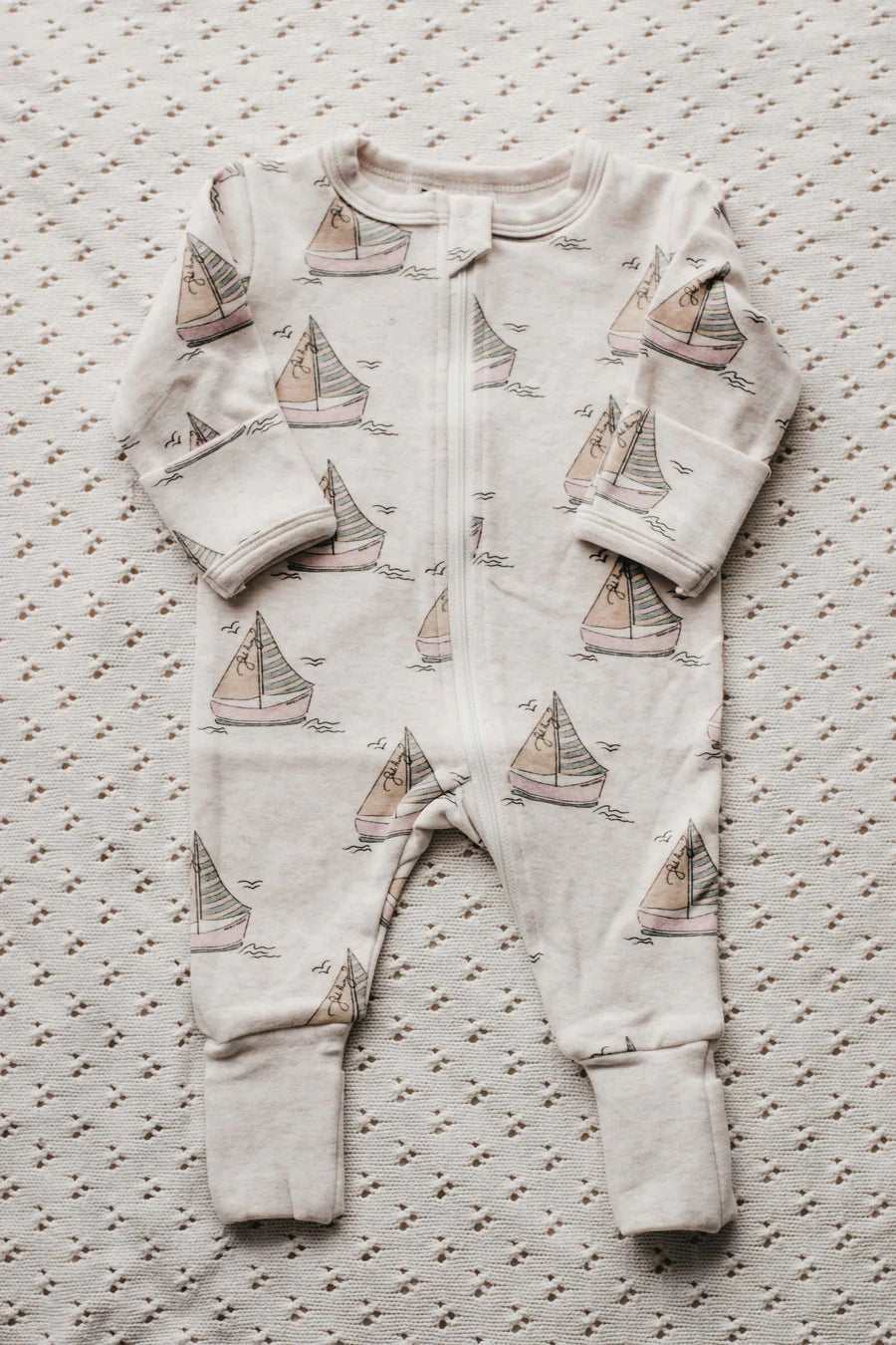 Baby onesie with sailboat pattern on a textured surface